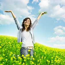 Young woman in a field of flowers very happy about not having allergy symptoms.