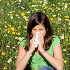 Girl suffering from allergies in a field of flowers.