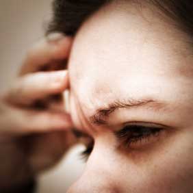 Woman with her hand on her forehead suffering from a headache or migraine.