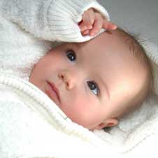 Very cute baby laying down with white blanket.