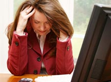 Woman rubbing temples stressed out working at her desk.